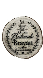 Rodela de madeira natural gravada a laser com texto 'O meu Batizado Brayan' e data, decorada com ramos e pombinha — vista frontal