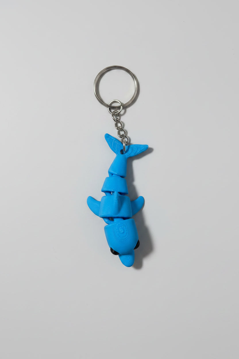 Porta-chaves golfinho 3D articulado suspenso pela argola, mostrando articulações do corpo