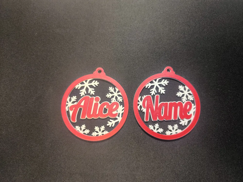 Duas bolas de Natal vermelhas e brancas com flocos de neve e os nomes Alice e Name, sobre fundo escuro.